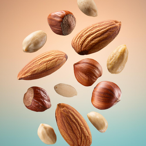 Almonds, hazelnuts, peanuts, all floating against a pastel gradient background